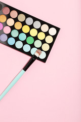 Makeup palette and brush on pink background. Minimalism concept