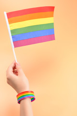LGBT flag in woman hand on orange background. Copy space.