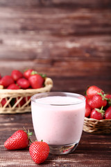 Smoothie in glass with strawberries on brown wooden table