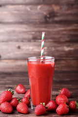Smoothie in glass with strawberries on brown wooden table