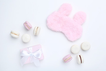 Sweet macarons with gift box and sleeping mask on white background. Minimalism concept