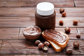 Bread with melted chocolate and hazelnuts on wooden table