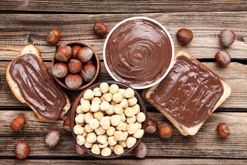 Bread with melted chocolate and hazelnuts on brown wooden table