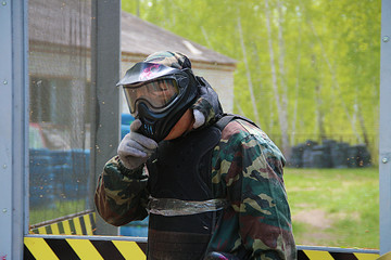 paintball sport player wearing protective mask aiming gun from shelter under gunfire attack with paint splash