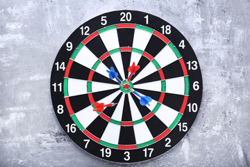 Dartboard with darts on grey wooden table