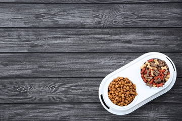 Obraz na płótnie Canvas Dry pet food in bowls on black wooden table