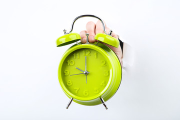 Hand holding alarm clock from white torn paper
