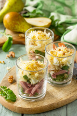 Salad with Pear, Ham, Egg, Walnuts, Fruits and Arugula on rustic wooden table.