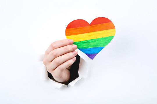 Hand Holding Paper Rainbow Heart From White Torn Paper