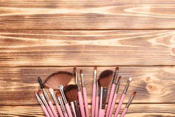 Set of makeup brushes on brown wooden table
