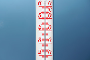 Thermometer during hot weather with sky in background