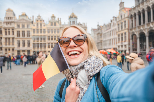 Woman tourist stands with the flag of Belgium on the background of the Grand-Place or the Grand Market Square in Brussels
