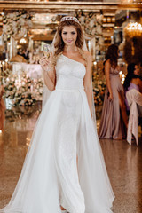 Naklejka premium Sharming Character Bride with Glass of Champagne. Portrait of Beautiful Happy Smiling Woman in Wedding Dress with Long Hair Luxury Delight Celebratory Make-up Standing in Ceremony Room