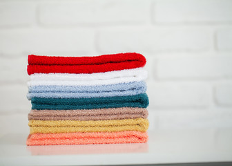 Colorful cotton towels in bathroom on white wooden table