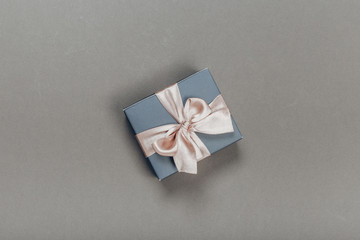 beautiful gift box wrapped in paper with gold and pink ribbon on a beige surface. Top view