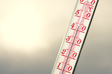 Thermometer during hot weather with sun in background