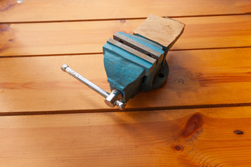 A blue vice is laying on a wooden surface