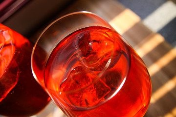 close up of red cocktail with ice cubes in wine glass