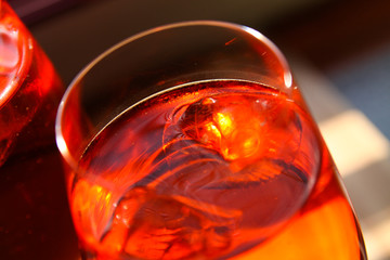 close up of red cocktail with ice cubes in wine glass