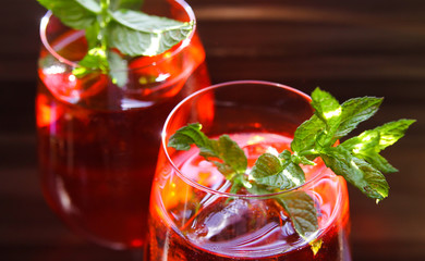 Close up of red cocktail with ice cubes green mint leaves in wine glass