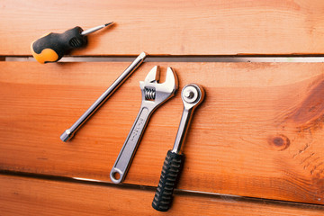 A various assortment of tools is laying on a wooden surface