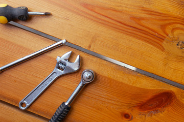 A various assortment of tools is laying on a wooden surface