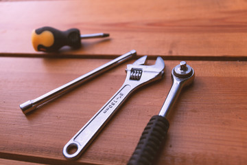 A various assortment of tools is laying on a wooden surface