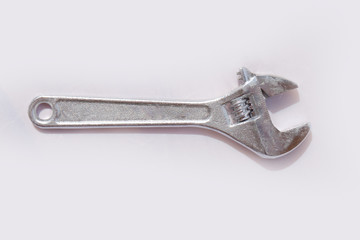 A silver wrench is laying on a white surface isolated on white background