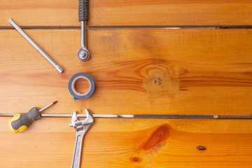 A various assortment of tools is laying on a wooden surface
