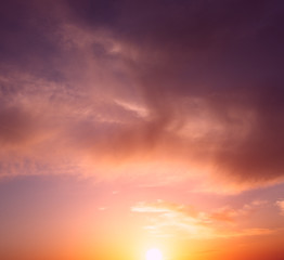 Fototapeta na wymiar The bright orange sun rises against the backdrop of purple clouds.
