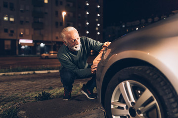 Naklejka premium Senior man washing his car in the evening at car wash station.