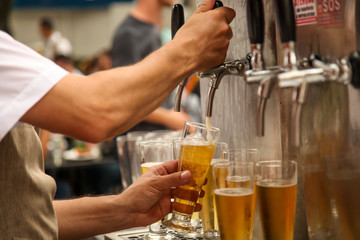 Fototapeta na wymiar Bartender serving tap beer on a unfocused party background