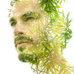 Double exposure of a young handsome man’s portrait blended with bright green leaves, showing the...