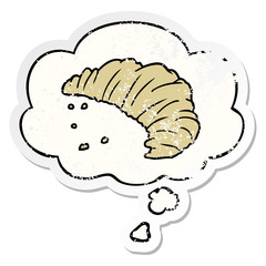 cartoon croissant and thought bubble as a distressed worn sticker