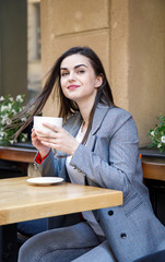 Young business woman having a coffee break at the street cafeteria