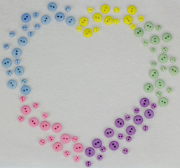 heart frame made of multi-colored buttons on white background