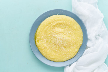 Urkainian polenta porridge on pastel turquoise aquamarine background top view copy space