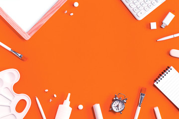Assorted office and school white stationery on bright orange background with alarm clock. Flat lay with copy space for back to school or education and craft concept monochromatic