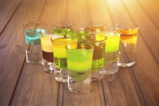 Colourful shot drinks on a white background with reflections