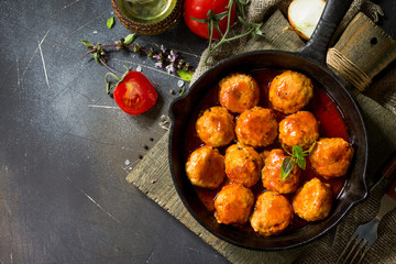 Homemade Meatballs with spices and tomato sauce in a frying pan on dark stone table. Free space for your text. Flat lay, top view background.