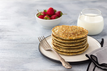 Vegan pancakes with flax seeds, strawberry and vegan milk on a white plate on a gray background, free space. delicious homemade healthy food