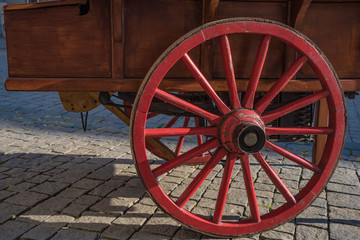 Rotes Wagenrad aus Holz auf Kopfsteinpflaster