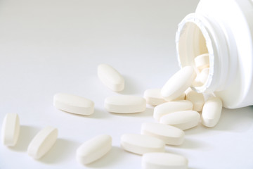 Medicine pills and a bottle of medicine isolated on a bright background