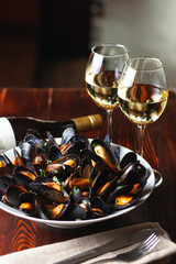 Fine dining in a seafood restaurant: a big dish of mussels with bottle of white wine with two wine...