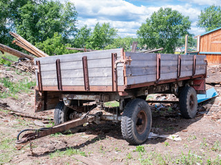 An old cart stands in a Russian village, against the background of a destroyed house, under the...