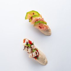Traditional spanish appetizer ? pinchos ? on white french baguette with salmon and avocado, trout and greens isolated on white background