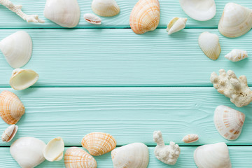 Fototapeta na wymiar shells frame and seaside background for blog or desktop on mint green wooden table top view mockup