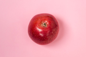 Fresh red apple on a plain pink background. Healthy food concept.