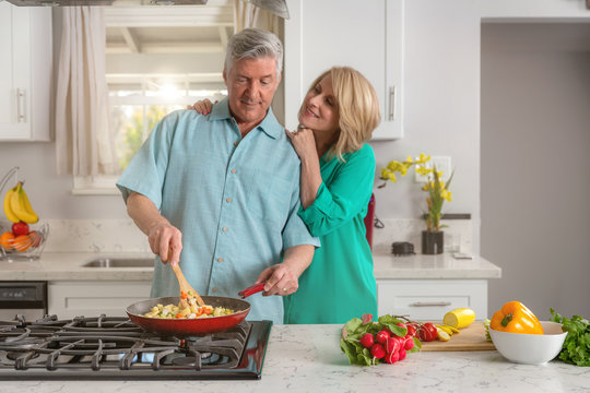 Adorable loving mature couple cooking together at home kitchen, candid lifestyle, healthy living
