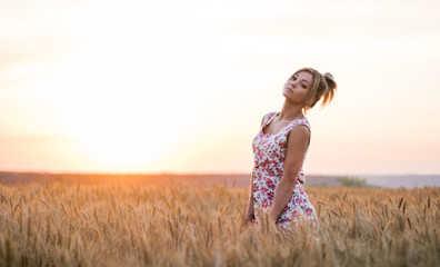 young seductive rural blond hair woman in dress on the yellow wheat field on the sunset, lake on the background